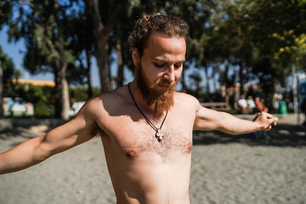 Uomo barbuto in fase di riscaldamento prima del suo allenamento sulla spiaggia