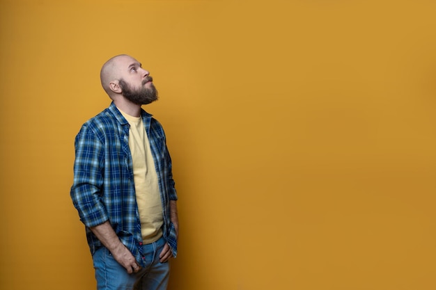 Bearded man wearing plaid shirt on yellow background isolated
with copy space happy successful man