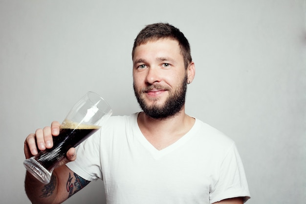Bearded man in a white T-shirt holding a pint glass