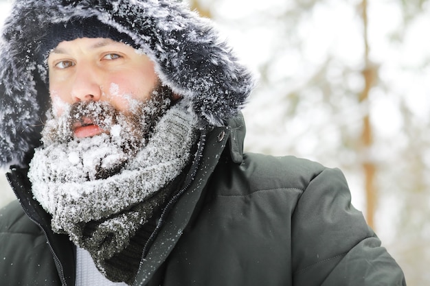 Foto uomo barbuto nei boschi invernali. attraente giovane felice con la barba a piedi nel parco.