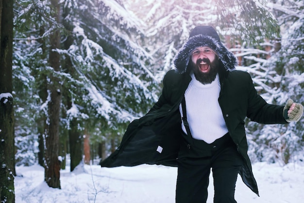 Bearded man in the winter woods. Attractive happy young man with beard walk in the park.