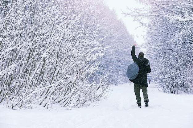 冬の森のひげを生やした男。あごひげを生やした魅力的な幸せな若い男が公園を散歩します。