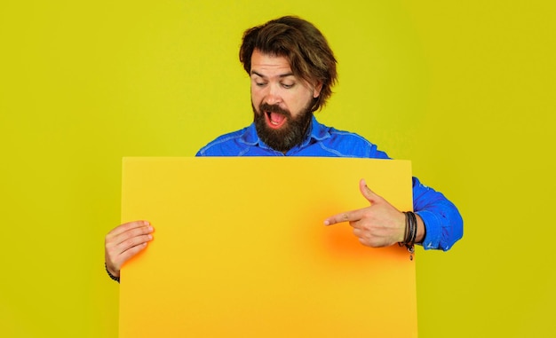 Bearded man with advertising board pointing finger at copy space shopping season sale discount