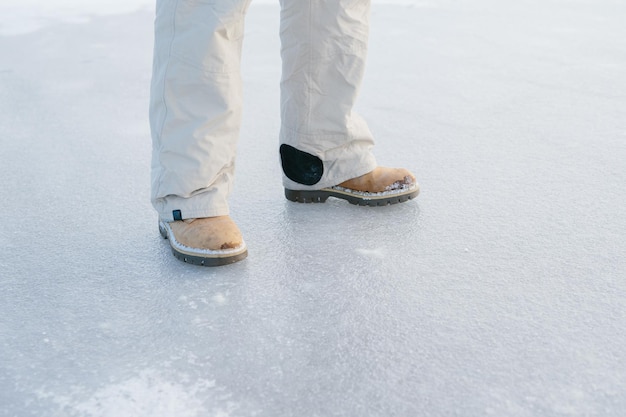 暖かい冬の服を着たバックパックを持ったひげを生やした男が、冬に凍った湖の上を歩いている ハイキングとアクティブなライフスタイルのコンセプト