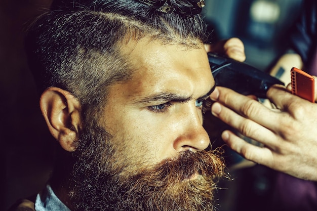 Uomo barbuto con la barba che si fa tagliare i capelli dal parrucchiere al barbiere