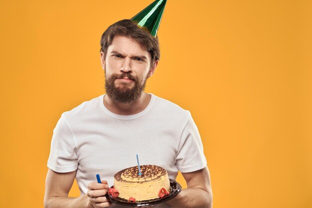 A bearded man with a cake and in a cap celebrating his birthday person