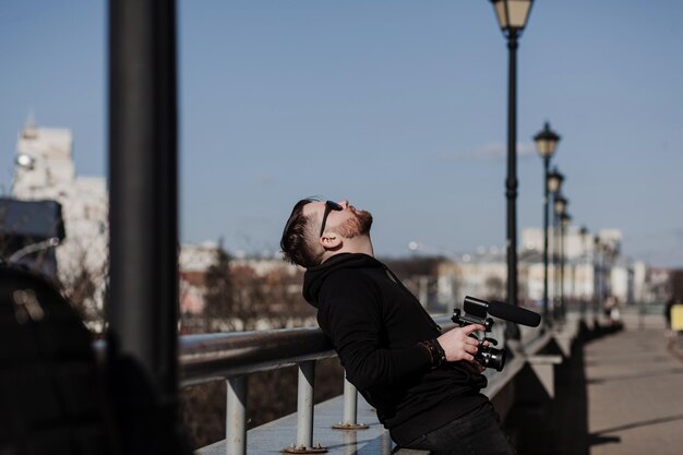 Бородатый мужчина с фотоаппаратом отдыхает в городе после работы