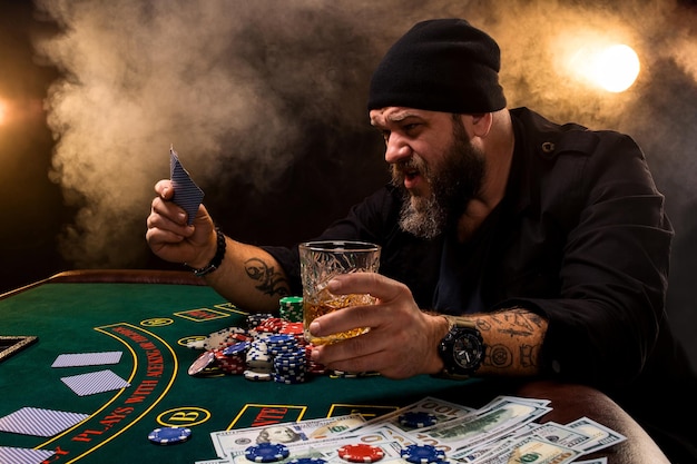 카지노에서 포커 테이블에 앉아 시가와 유리 수염된 남자. 도박, 카드 놀이 및 룰렛.