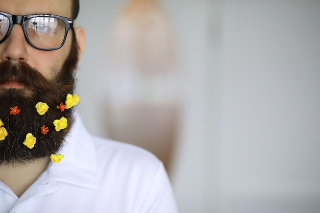 A bearded man with a decorated beard for the Spring holiday. Flowers in the beard.