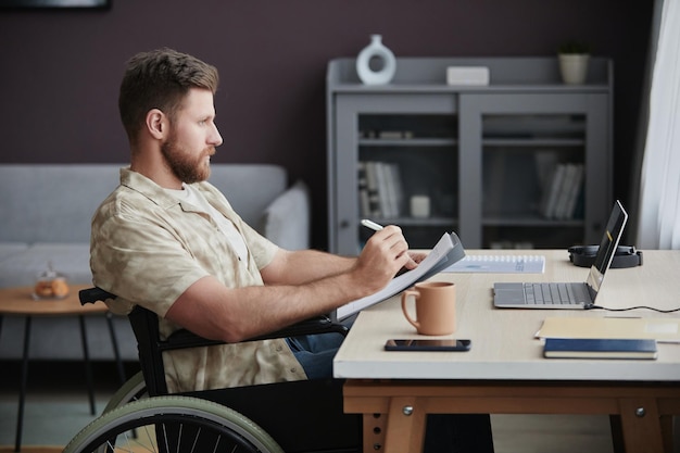 Photo bearded man with disability coding while working at home office