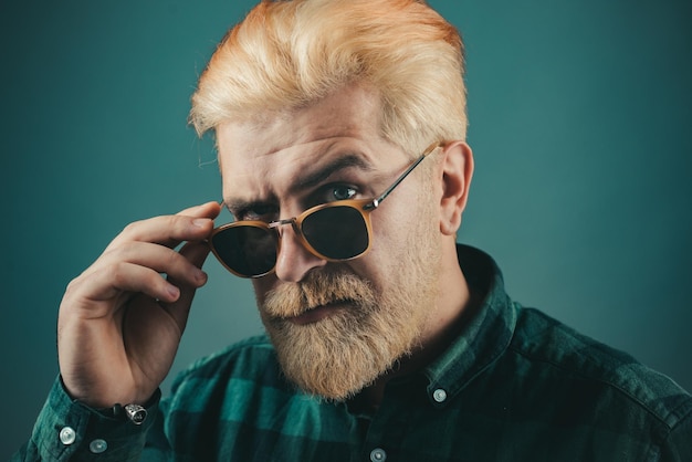 Bearded man with fashion sunglasses Close up portrait of a very handsome man Beautiful guy in shirt looking to the camera isolated over grey background