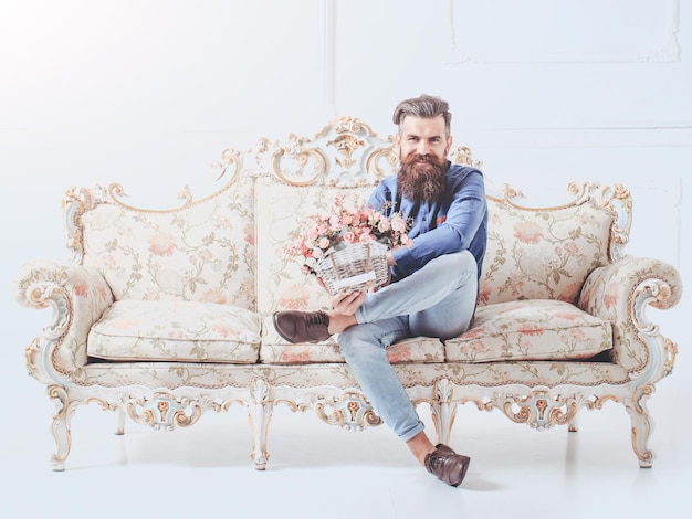 Бородатый мужчина с цветами на диване