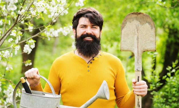 Foto uomo barbuto con attrezzi da giardinaggio giardiniere con pala e annaffiatoio che si prepara a piantare piante