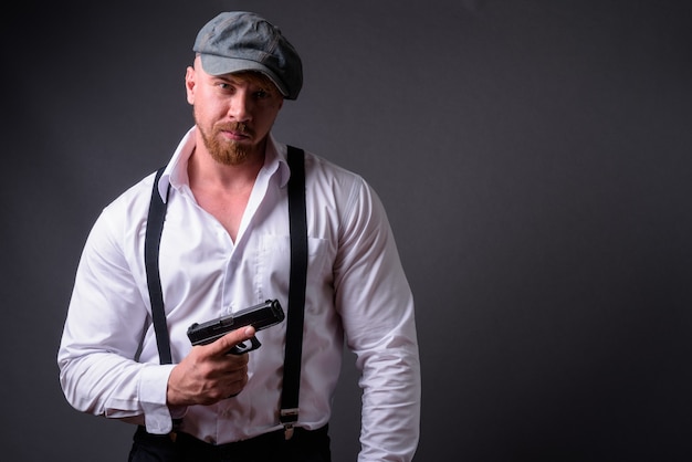 Bearded man with handgun on gray