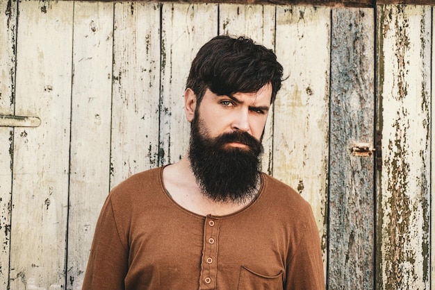 Bearded man with long beard and moustache on wooden background Male serious face