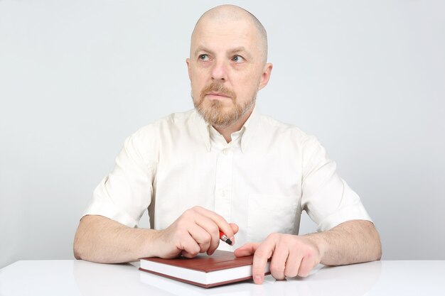 Bearded man with a notebook and a pen in his hands thinks