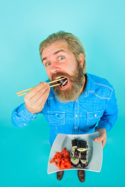 Bearded man with plate of sushiroll man eating sushi sushi man\
with sushi on chopstick japan sushi
