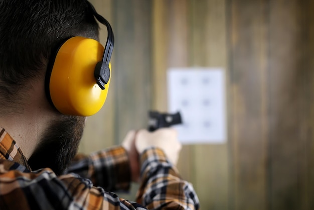 Bearded man with put on protective goggles and ear training in pistol shooting