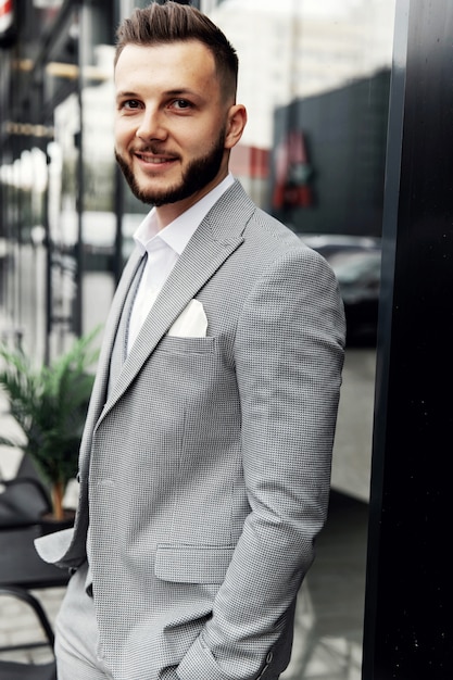 A bearded man with a red beard in a shirt, vest and glasses.
