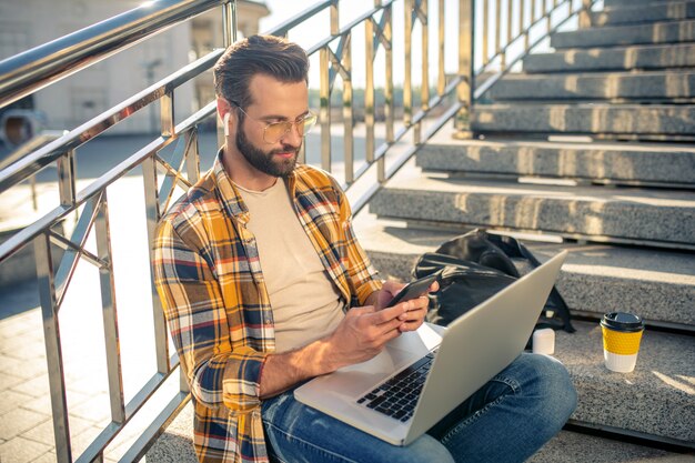 Bearded man working on a laptop on the stairs