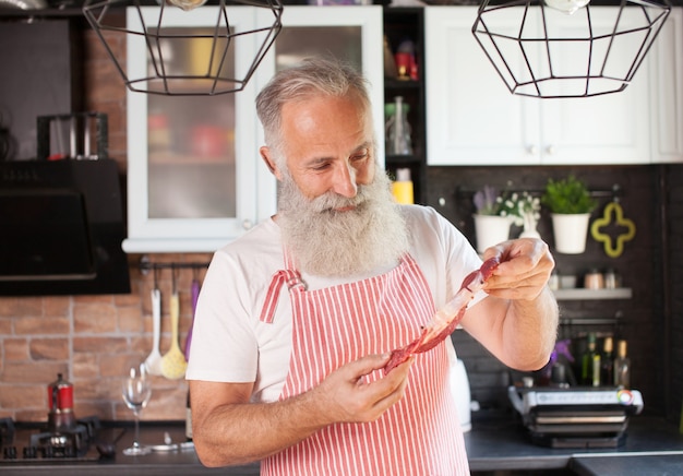 Uomo maturo barbuto che tiene una carne cruda del manzo.