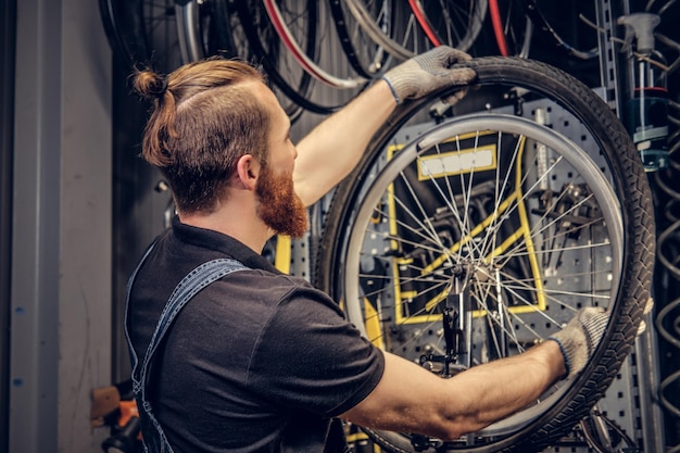 ワークショップで自転車のホイールタイヤを修理するひげを生やした整備士。背面図、サービスマニュアル。