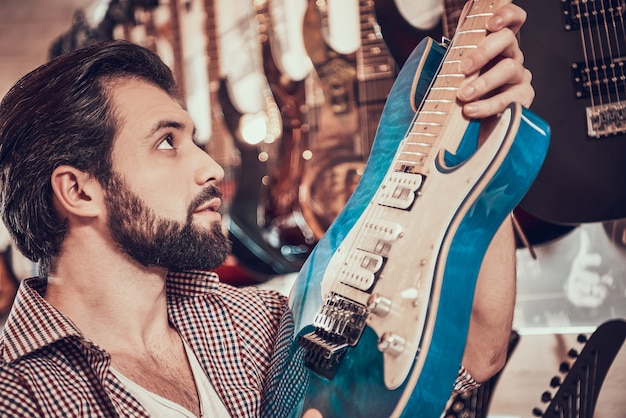 Bearded musician chooses electric guitar in store