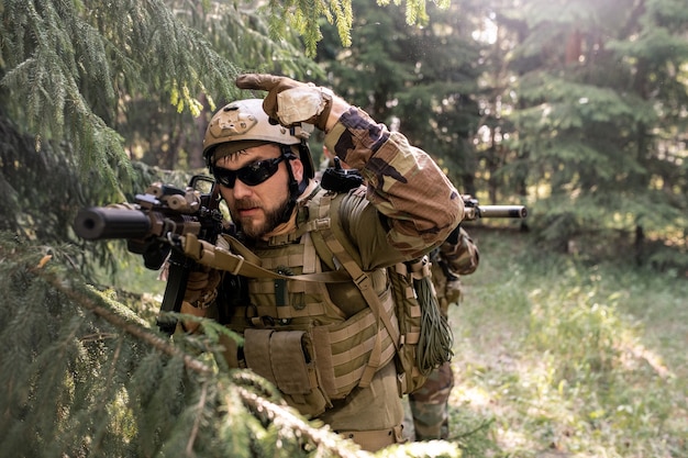 Bearded officer in helmet and sunglasses counting down before attack while conducting military operation in forest