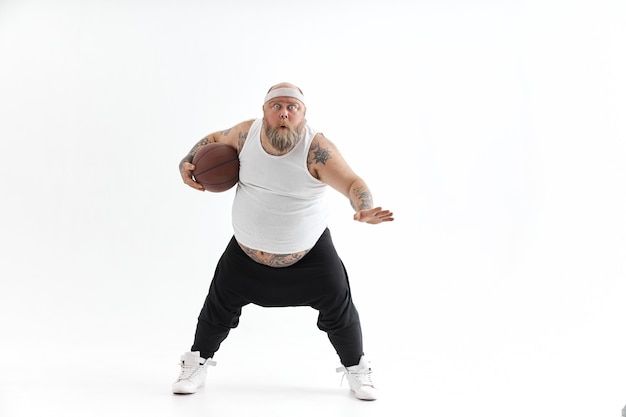 Бородатый толстый татуированный мужчина с баскетбольным мячом на белом фоне