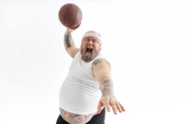 Bearded overweight tattooed man with basketball ball in white background