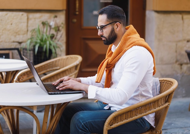 Bearded professional businessman using modern laptop outdoors