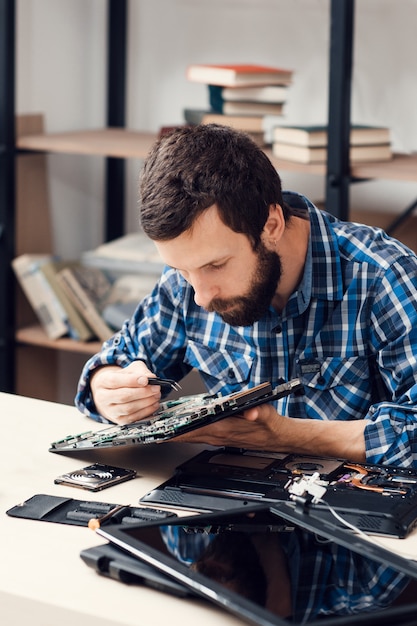 Bearded repairman disassembling computer