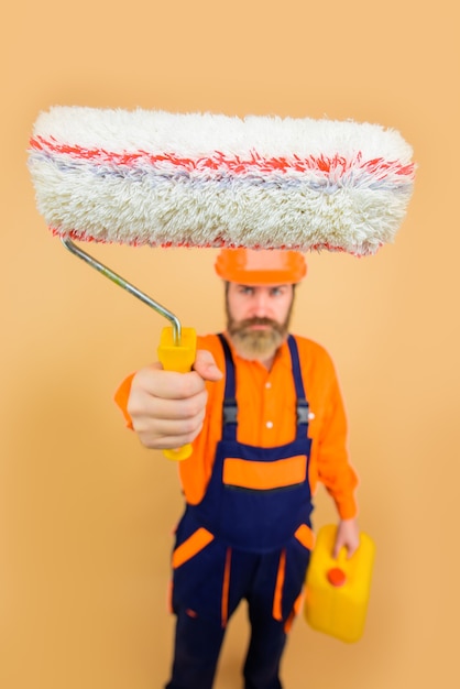 Фото Бородатый ремонтник в униформе держит малярный валик, ремонтник, профессиональный художник-дизайнер в полный рост