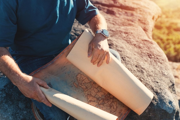 Il pensionato barbuto sta cercando una destinazione sulla mappa sullo sfondo dei campi