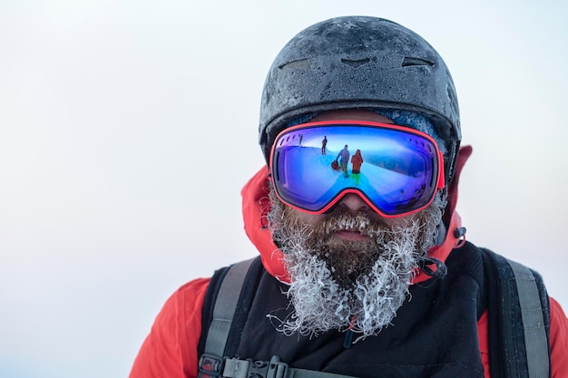 사진 얼어붙은 헬멧과 마스크를 쓴 수염 난 스키어가 프리라이더 팀을 막고 있습니다.