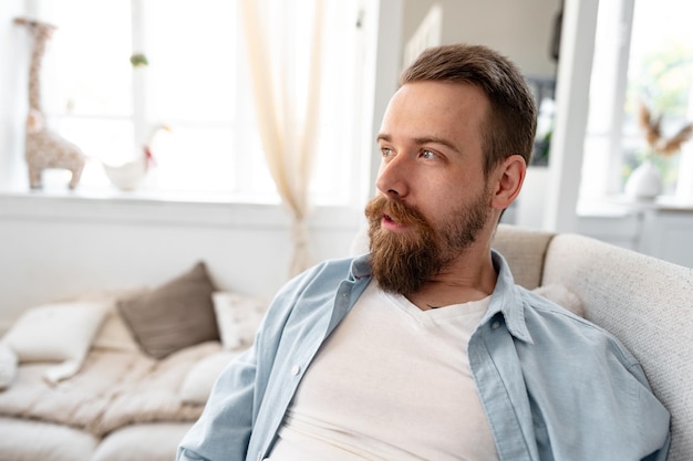Портрет бородатого улыбающегося красивого молодого человека в одиночестве дома