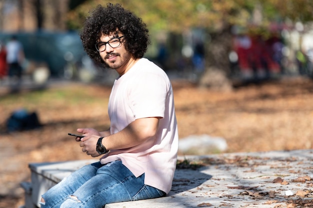 Bearded Smiling Man Touching Phone in Park