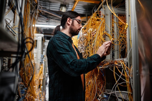 Bearded system administrator setting up network in server room