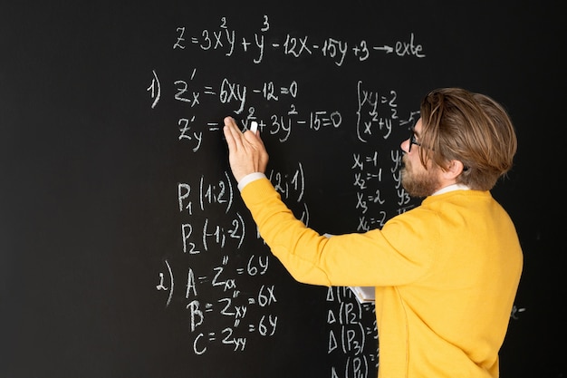 Bearded teacher in casualwear rewriting formulas on blackboard from his copybook before giving task to his online audience