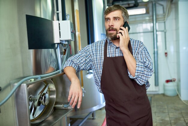 Foto tecnico barbuto che per mezzo del telefono cellulare