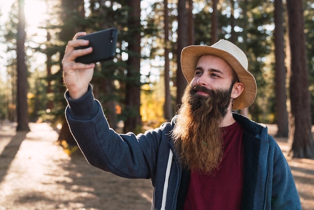 Bearded tourist taking selfie in woods