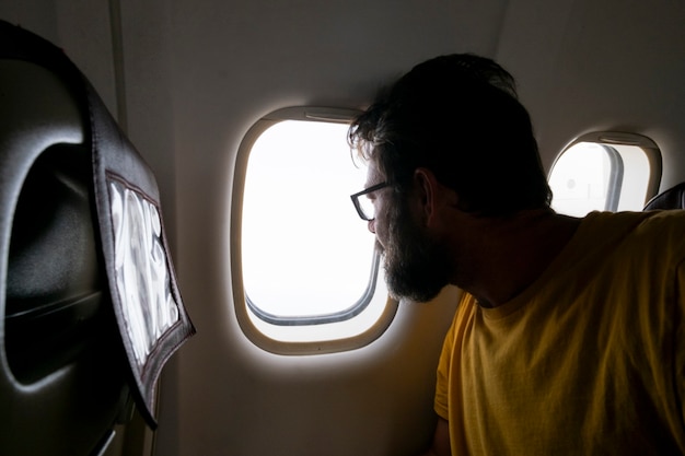 Bearded traveler man look outside the window inside the airplane flying and traveling