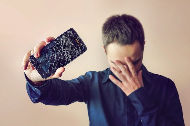 Бородатый расстроенный мужчина держит неиспользуемый планшет или смартфон. на светлом фоне. сломанный экран