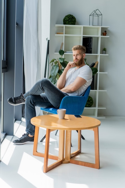 Bearded young businessman working at modern office.man wearing white t-shirt and making notes on the documents.