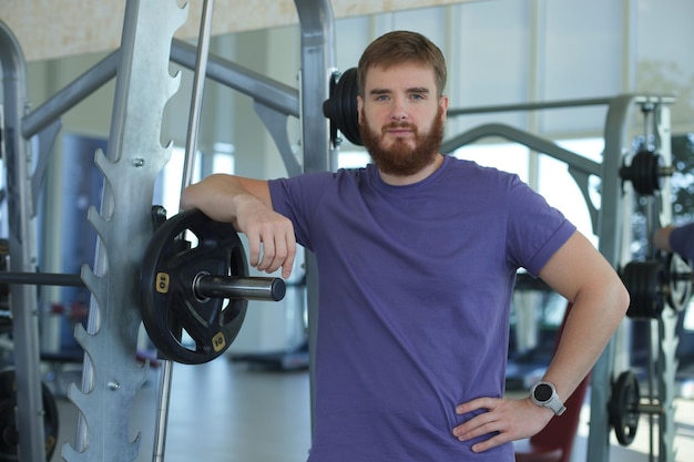 Bearded young man training in the gym and looking at camera