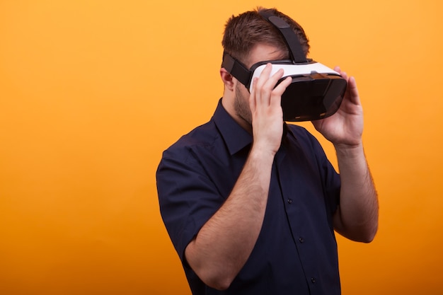 Bearded young man wearing VR headset over yellow background. Futuristic tool