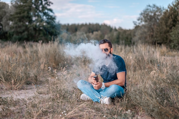 Beardedman blaast een koppel een e-sigaret op in de natuur. Vapen activiteit.