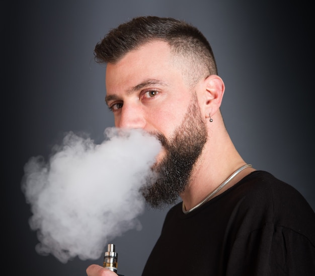 Uomo barbuto che fuma sigaretta elettronica