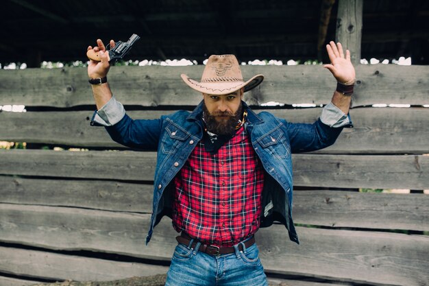 beared man with hat and a gun