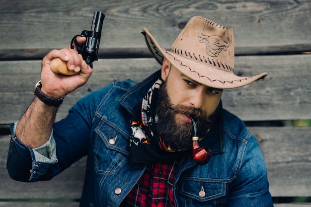 beared man with hat and a gun